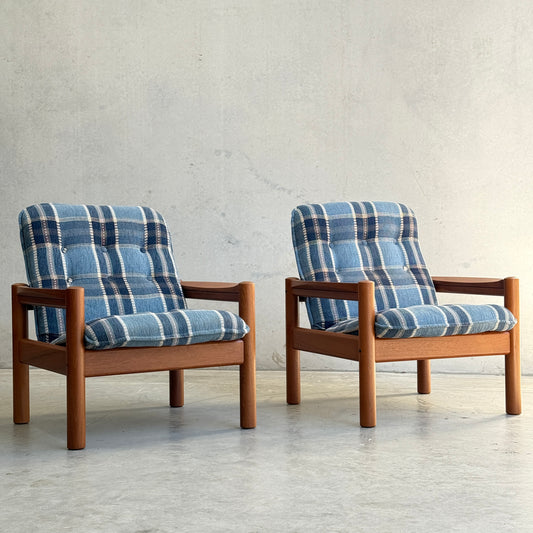 Two Restored Domino Møbler Armchairs from the Blue Plaid Mid-Century Set (Rediscover) sit side by side on a light concrete floor against a plain light gray wall.