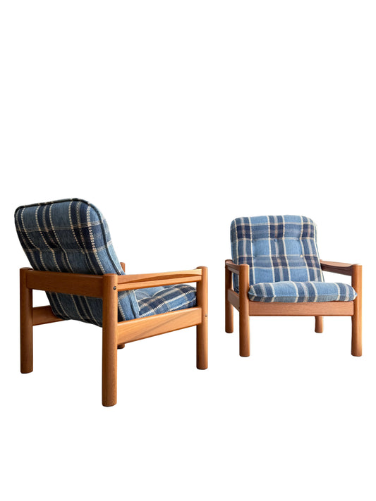 Two Restored Domino Møbler Armchairs – Blue Plaid Mid-Century Set (Rediscover) are set on a white background: one angled to show its side and back, the other facing forward, both featuring retro blue plaid cushions.