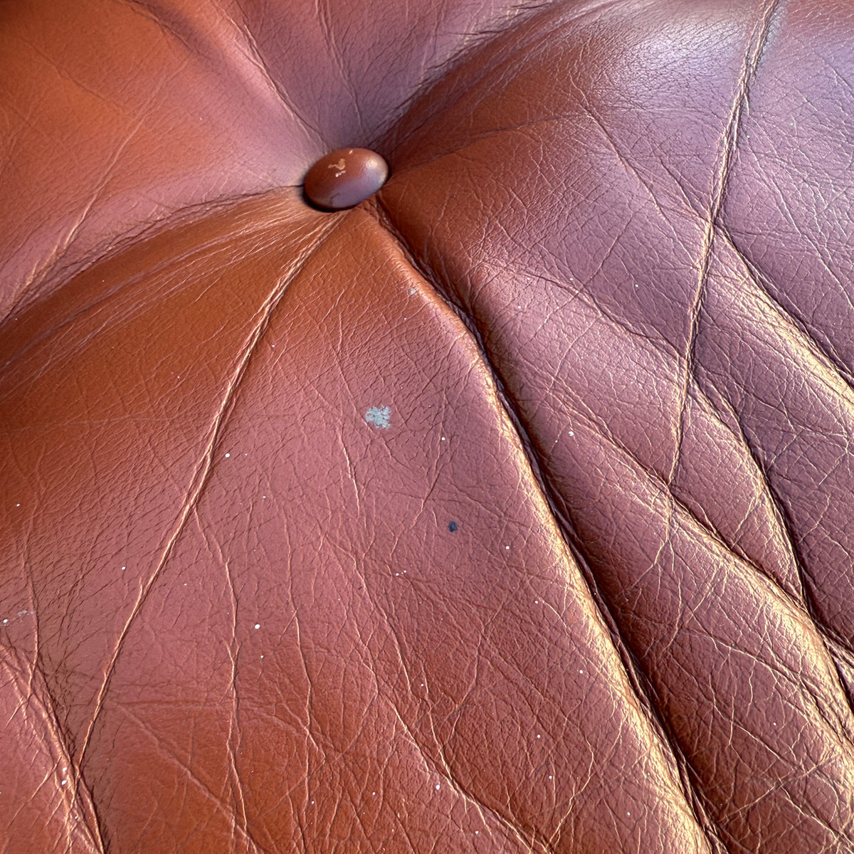 Close-up of a brown Howe leather cushion with a central button from the Rare Set of 4 Vintage Joe Rufenacht Lounge Chairs, showing creases and subtle marks that enhance their character and authentic vintage charm.