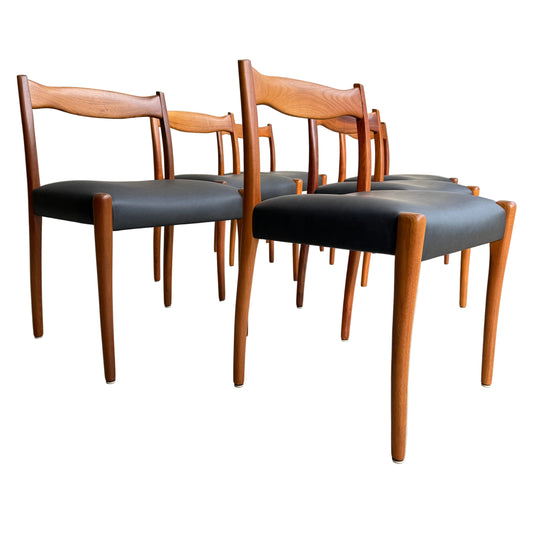 A fully restored set of 6 Fler 64 dining chairs with wooden frames and liquorice vinyl seats are arranged on a light concrete floor against a plain wall, showcasing a classic mid-century modern style.