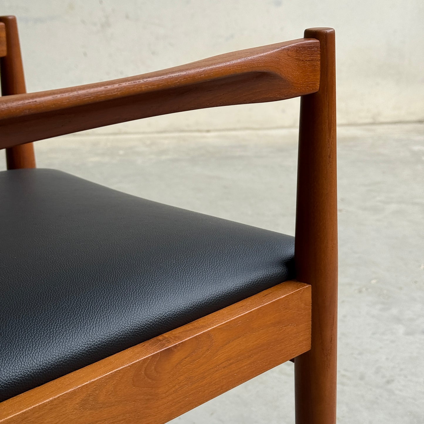 A close-up of a professionally restored Parker 89 Chair—Pre-Order: Professional Restoration of Parker 89 Chair (25% non-refundable deposit)—featuring a smooth dark brown frame and black premium vinyl seat, set against a plain wall and concrete floor.