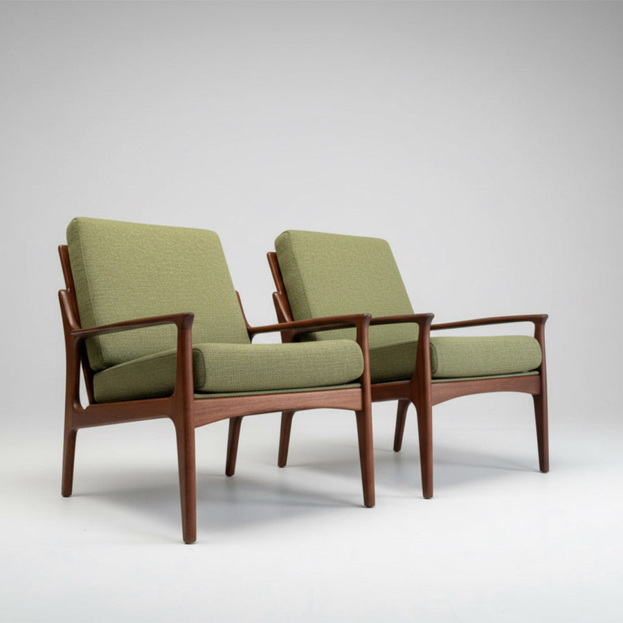 Two mid-century modern armchairs with green upholstered cushions and wooden frames are placed side by side on a plain white background.