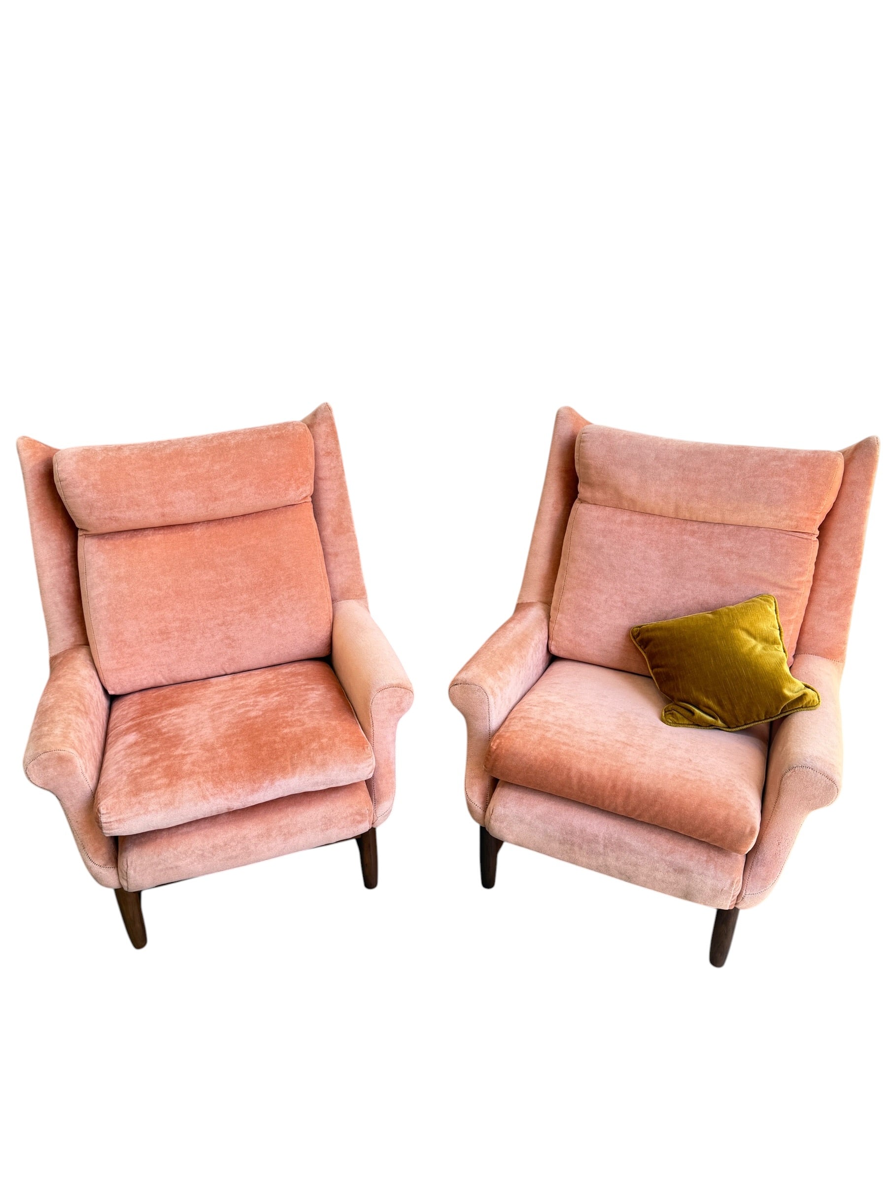 Two Mid-Century High-Back Wingback Armchairs in dusty pink velvet with Blackwood frames sit side by side against a white background. One armchair has a green throw pillow; the other is empty. Priced individually from Rediscover.