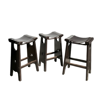 A set of three 1970s Australian Mid-Century Modern Spanish Revival Davis Stools is arranged on a light floor in a sunlit room, with sunlight from the right casting shadows.