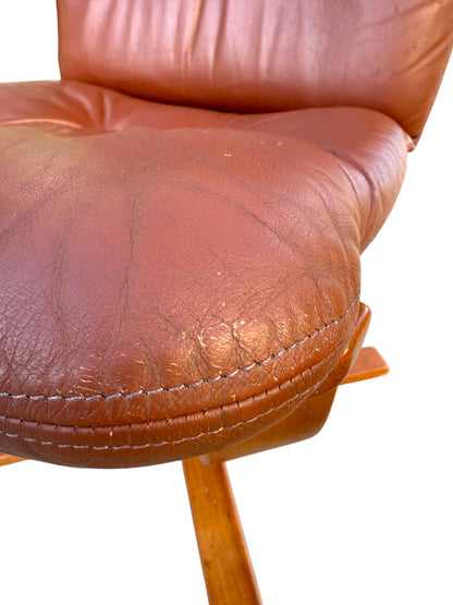 Close-up of a rare Howe Leather Joe Rufenacht lounge chair, showing brown leather seat with creases and stitching on wooden legs. From a set of 4 vintage Scandinavian design chairs, isolated on white background.