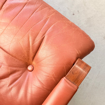 Close-up of a light brown leather cushioned seat with a button tuft and wrinkles, set in a wooden frame that reflects Fred Lowen’s mid-century style, seen in the Tessa T8 Lounge Suite modular two-seater sofa & armchairs (Revive).