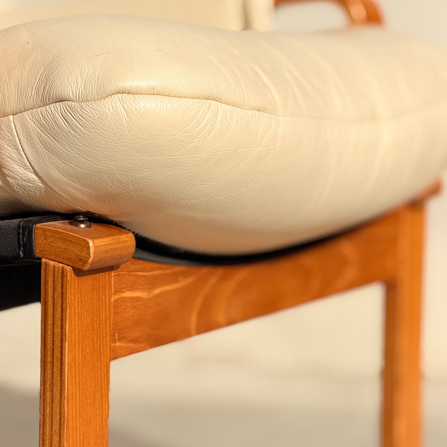 Close-up of the Tessa Austin Blonde Leather Armchair (Revive), featuring a cream-colored leather seat and light wood frame, showcasing the leather texture and smooth wood finish under warm lighting.