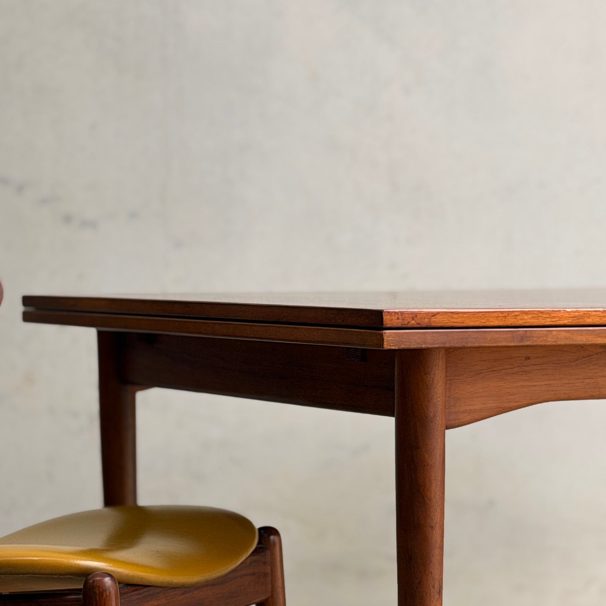 A close-up of the Vintage Mid-Century Parker 109 Nordic Extension Dining Table (Revive) featuring rounded edges, set against a plain, light-colored wall.
