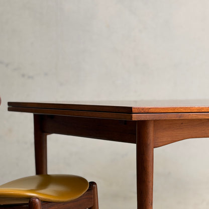 A close-up of the Vintage Mid-Century Parker 109 Nordic Extension Dining Table (Revive) featuring rounded edges, set against a plain, light-colored wall.