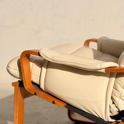 A close-up of the Tessa Austin Blonde Leather Armchair (Revive), featuring beige leather and wooden armrests, basking in warm sunlight against a neutral background.