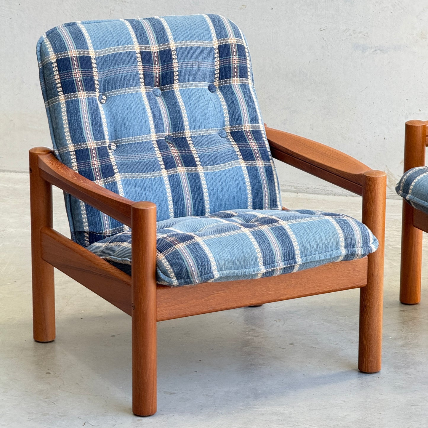 The Restored Domino Møbler Armchairs – Blue Plaid Mid-Century Set (Rediscover) features solid wood frames and cushioned seats with retro blue plaid upholstery, displayed on a light floor against a plain, light background.
