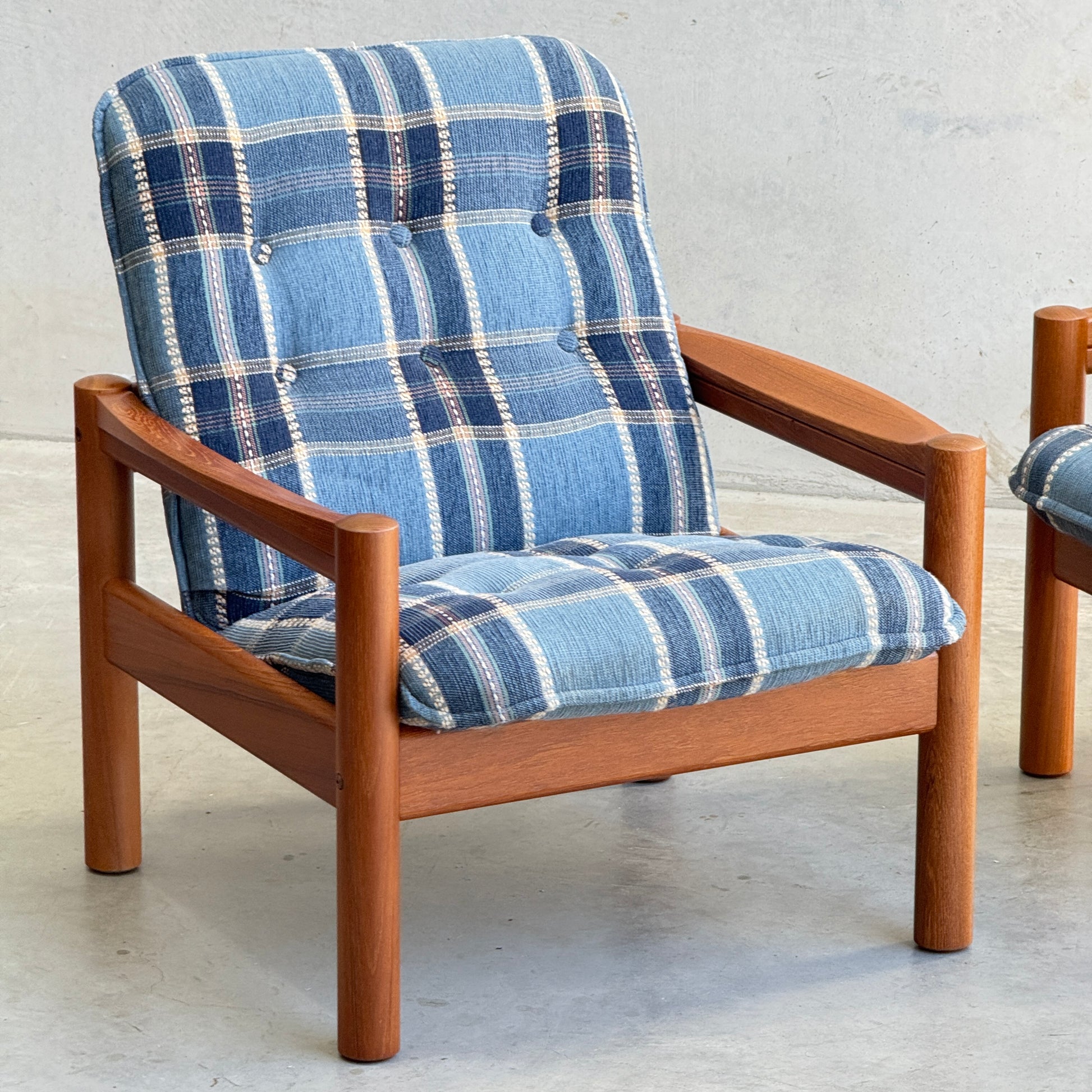 The Restored Domino Møbler Armchairs – Blue Plaid Mid-Century Set (Rediscover) features solid wood frames and cushioned seats with retro blue plaid upholstery, displayed on a light floor against a plain, light background.