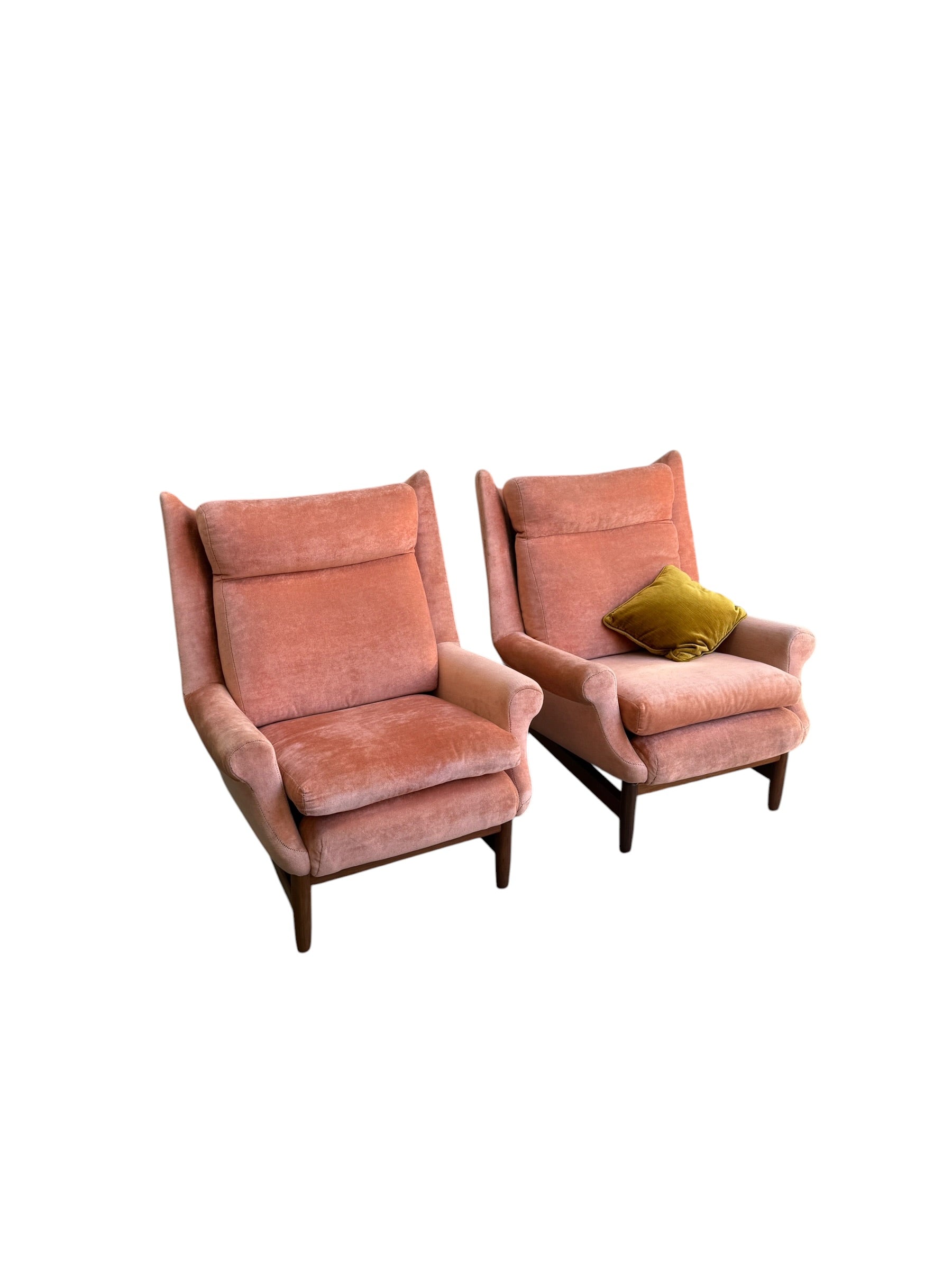 Two Mid-Century High-Back Wingback Armchairs in dusty pink velvet with blackwood frames are shown side by side on a white background. One chair features a green throw pillow. Priced individually from Rediscover.