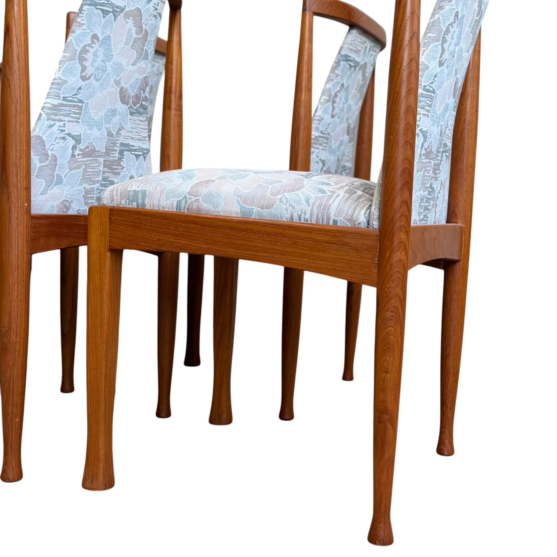 Six Vintage CRO Teak Dining Chairs from the Revive collection are arranged closely together, showcasing their legs and lower sections against a white background.