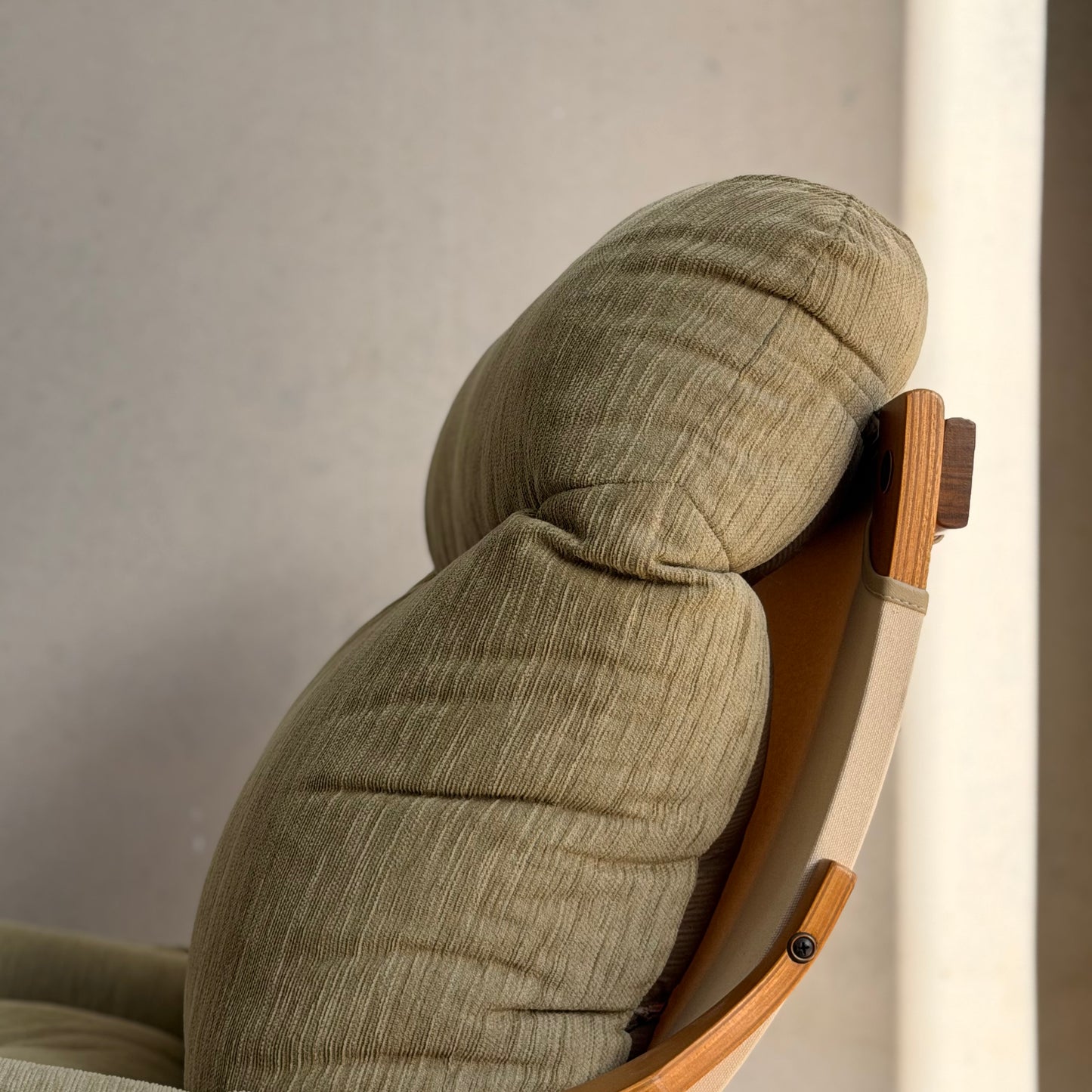 Close-up of a Pair of Tessa Monaco Arm Chairs in sage green corduroy—like new (Revive)—featuring cushioned seats, rounded headrests, and light wooden armrests, showcasing mid-century style against a neutral background.