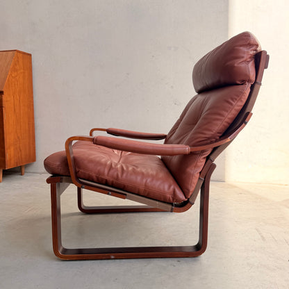 The Tessa T8 Lounge Suite modular two-seater sofa and armchairs (Revive) feature padded seats, armrests, and backrests on a wooden frame in mid-century style, set against a light wall with a wooden cabinet and natural light from the right.