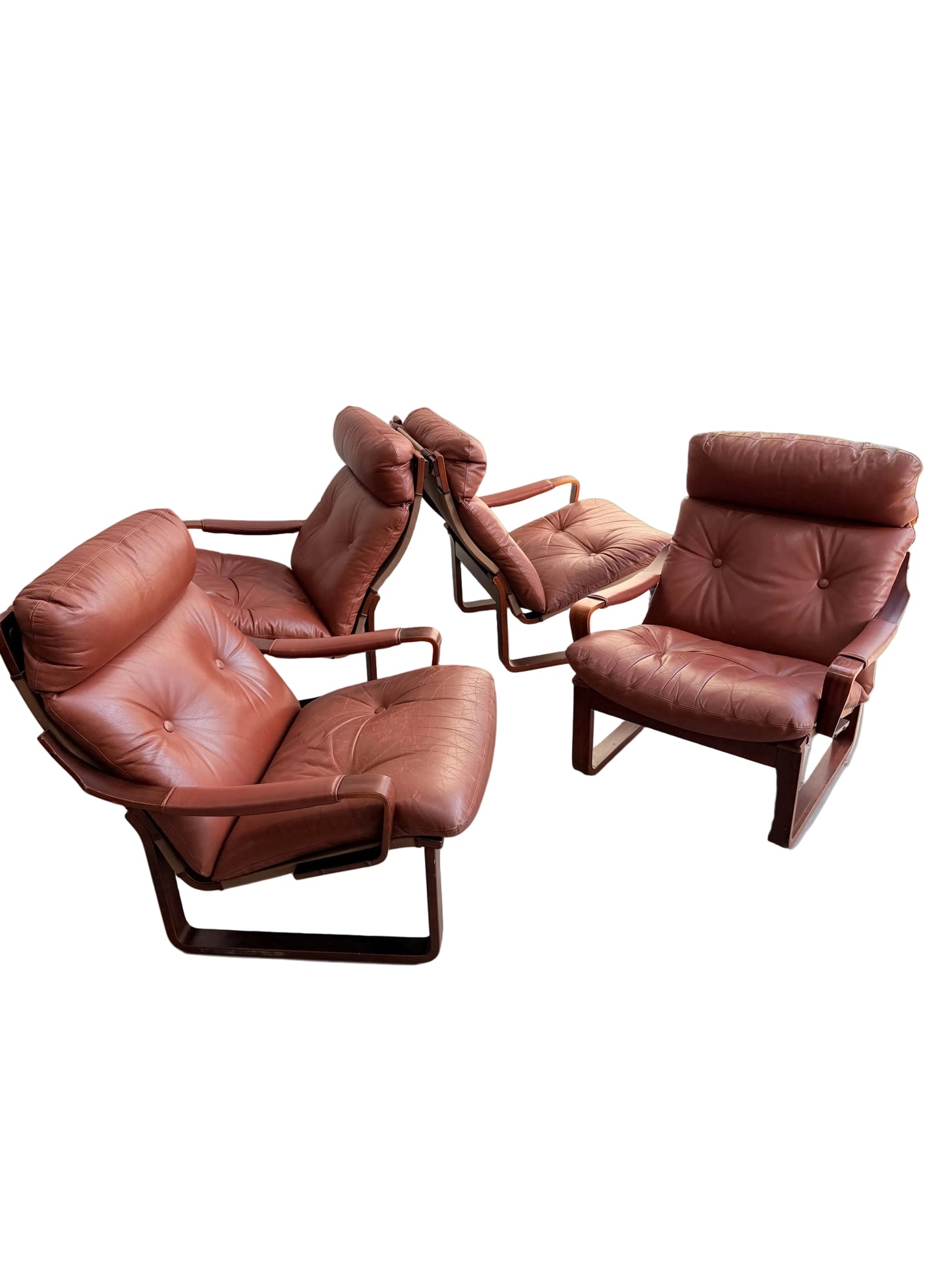 Three Tessa T8 Lounge Suite modular two-seater sofas and Revive armchairs, in vintage brown leather with padded seats and backs, are arranged on a light concrete floor against a plain wall in a well-lit indoor space.