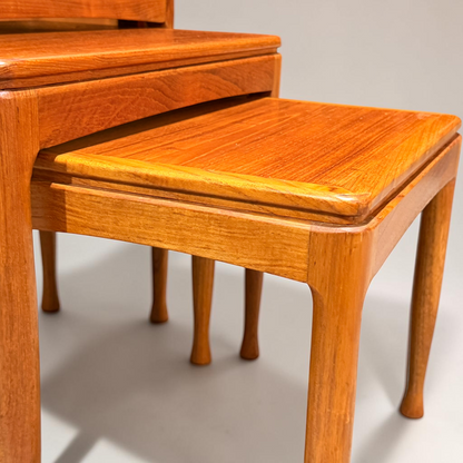 A close-up of the Rare set of Alpa Teak Nesting Tables – Set of 3 - Australian Mid-Century Modern (Revive), featuring polished teak surfaces, smooth edges, and curved legs, set against a plain background.