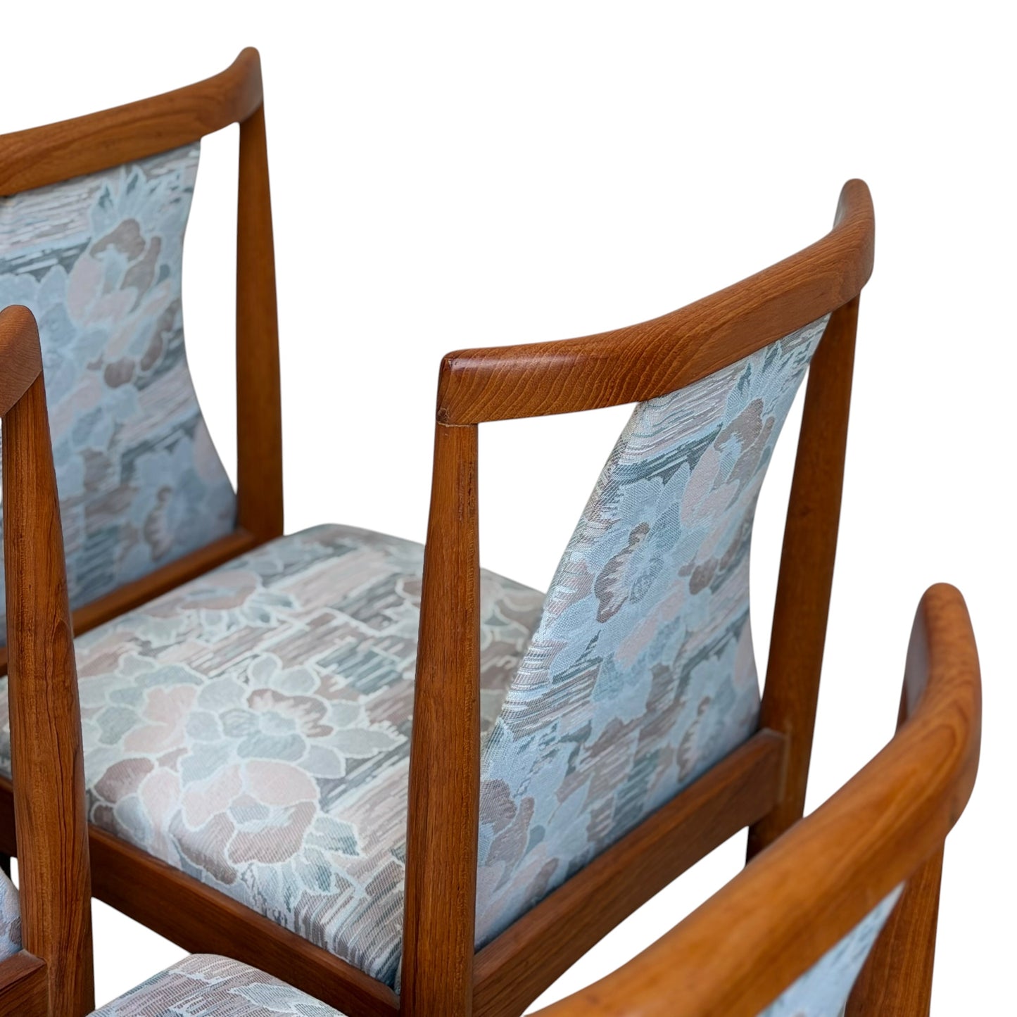 Six Vintage CRO Teak Dining Chairs with curved backs and light blue floral upholstery on seats and backrests, arranged closely together against a white background.