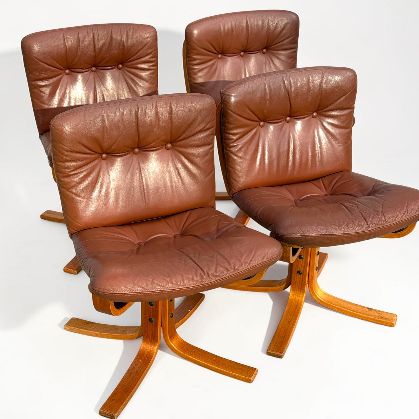 A rare set of 4 vintage Joe Rufenacht lounge chairs upholstered in Howe leather is arranged in two rows on a white background, showcasing curved wooden bases and Scandinavian mid-century modern style.