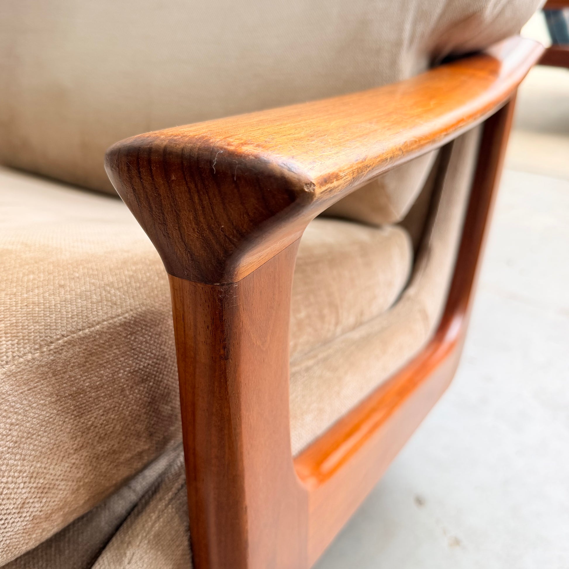 Close-up of the wooden armrest on a Vintage Mid Century Tessa T21 Swivel Chair (Revive), showcasing its smooth, curved design and rich wood grain details against a cream velvet cushion—a sophisticated mid-century accent.