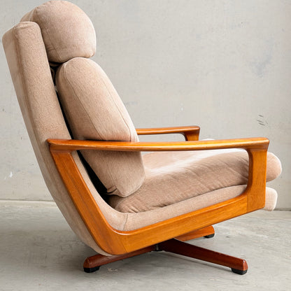 The Vintage Mid Century Tessa T21 Swivel Chair (Revive) features cream velvet upholstery and angled wooden armrests, shown in profile against a light wall—an iconic mid-century modern statement piece.