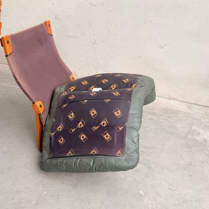 A worn Tessa Vintage Single No Arm Monaco Armchair – Forest Green (Revive) with a purple seat, green padding, patterned backrest, and orange frame sits on concrete. Its mismatched parts sag, lacking charm or leather details.