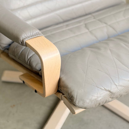 Close-up of the Tessa Ferrara Lounge Suite – Complete 5-Piece Set (Revive), featuring mid-century modern design, light wood armrests and legs, and cushioned seat and backrest in light gray, slightly wrinkled leather upholstery.