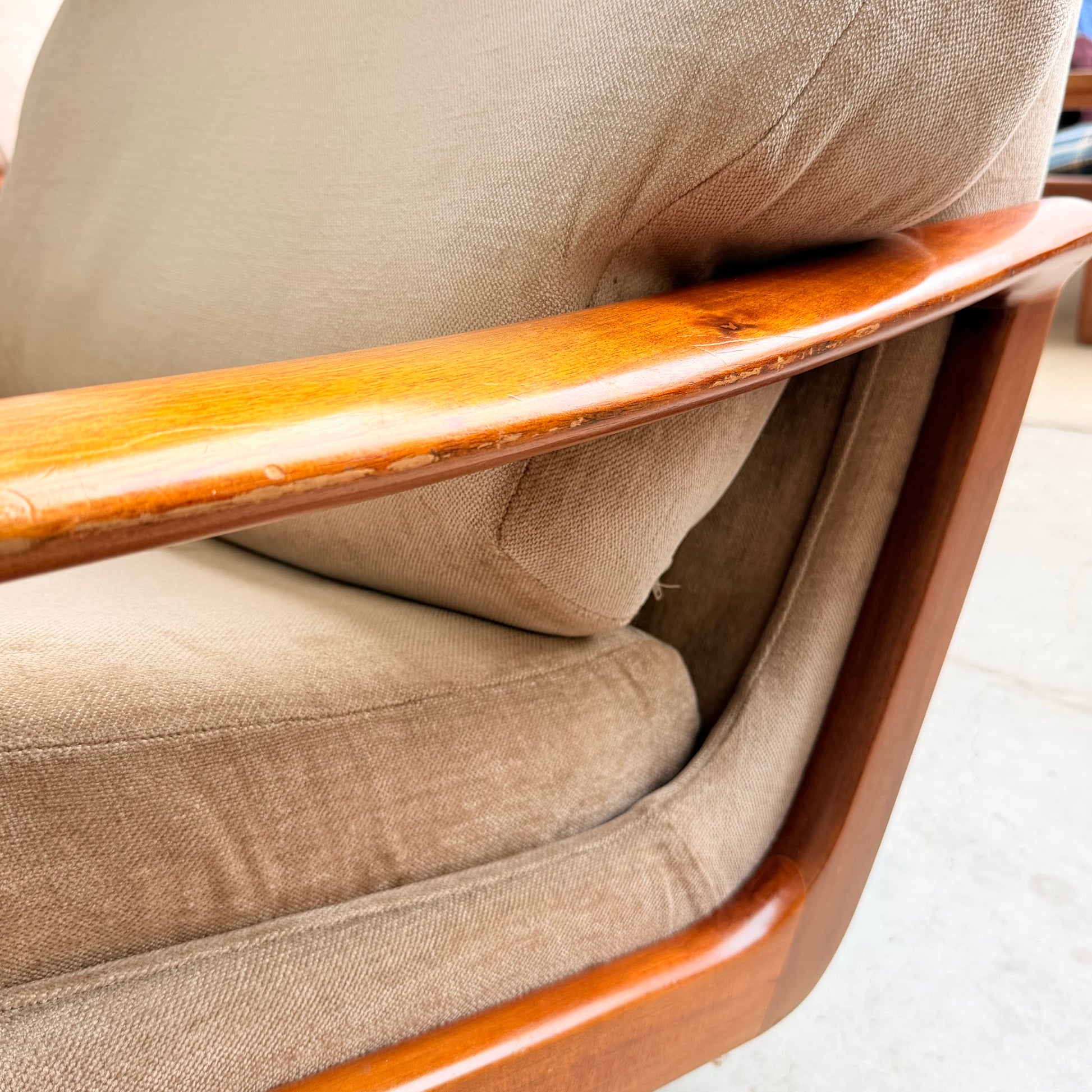 Close-up of the Vintage Mid Century Tessa T21 Swivel Chair (Revive) featuring light brown fabric and a curved wooden frame, showcasing elegant texture and wood grain—perfect for any mid-century collection.