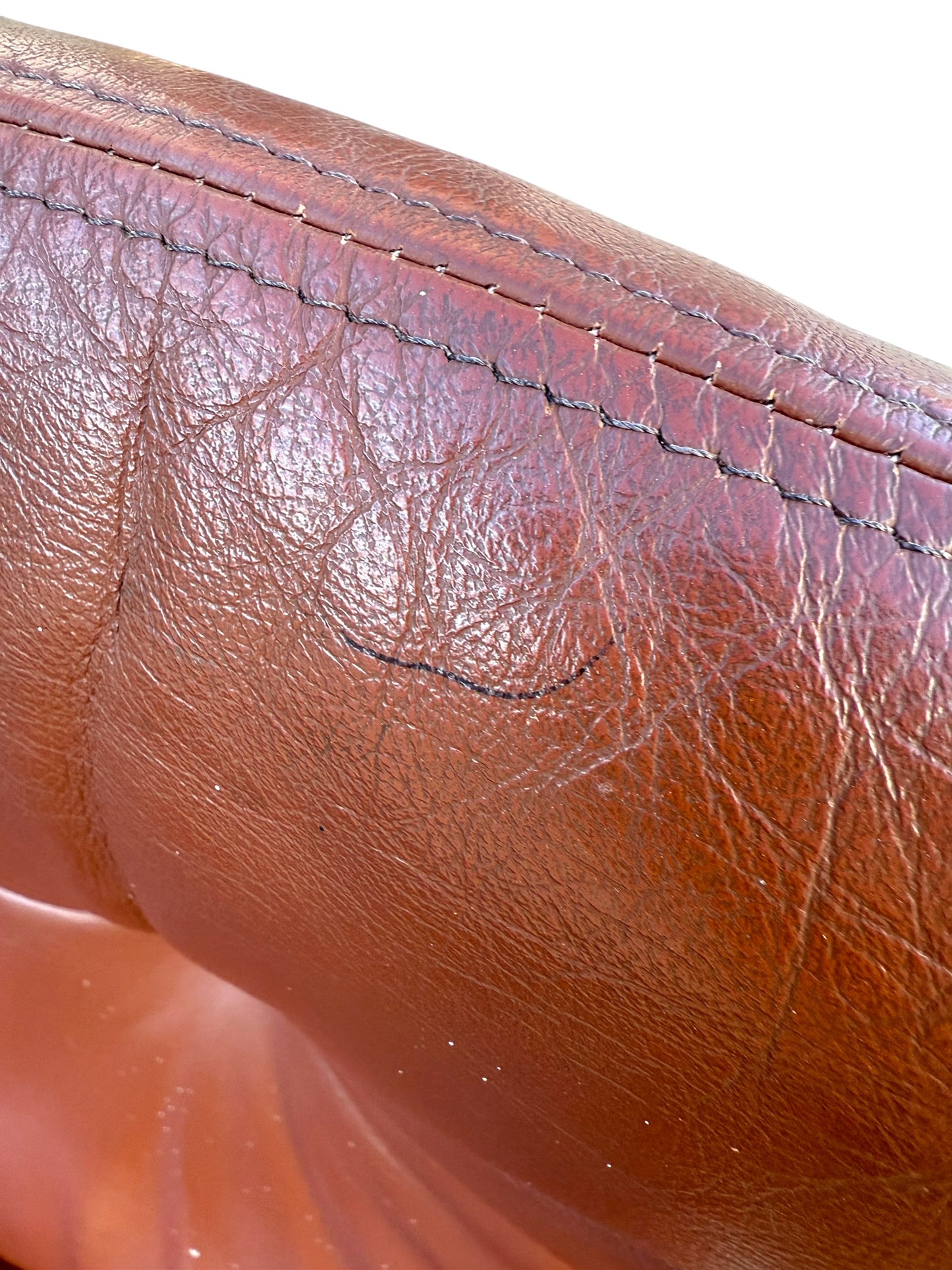 Close-up of worn Howe leather upholstery with creases, wrinkles, and subtle black scuffs. Distinct stitching accents the top edge, reflecting vintage Scandinavian style in this rare set of 4 Joe Rufenacht lounge chairs.