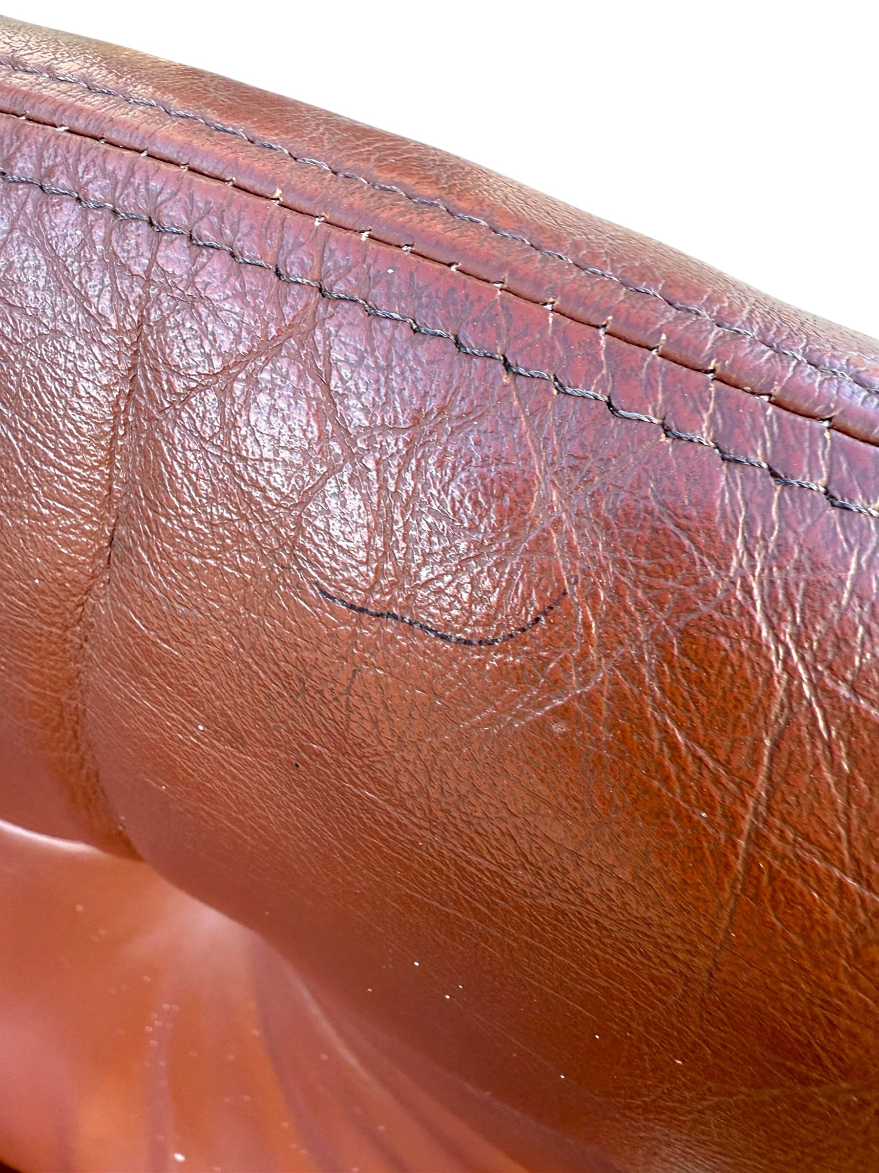 Close-up of worn Howe leather upholstery with creases, wrinkles, and subtle black scuffs. Distinct stitching accents the top edge, reflecting vintage Scandinavian style in this rare set of 4 Joe Rufenacht lounge chairs.