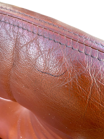 Close-up of worn Howe leather upholstery with creases, wrinkles, and subtle black scuffs. Distinct stitching accents the top edge, reflecting vintage Scandinavian style in this rare set of 4 Joe Rufenacht lounge chairs.