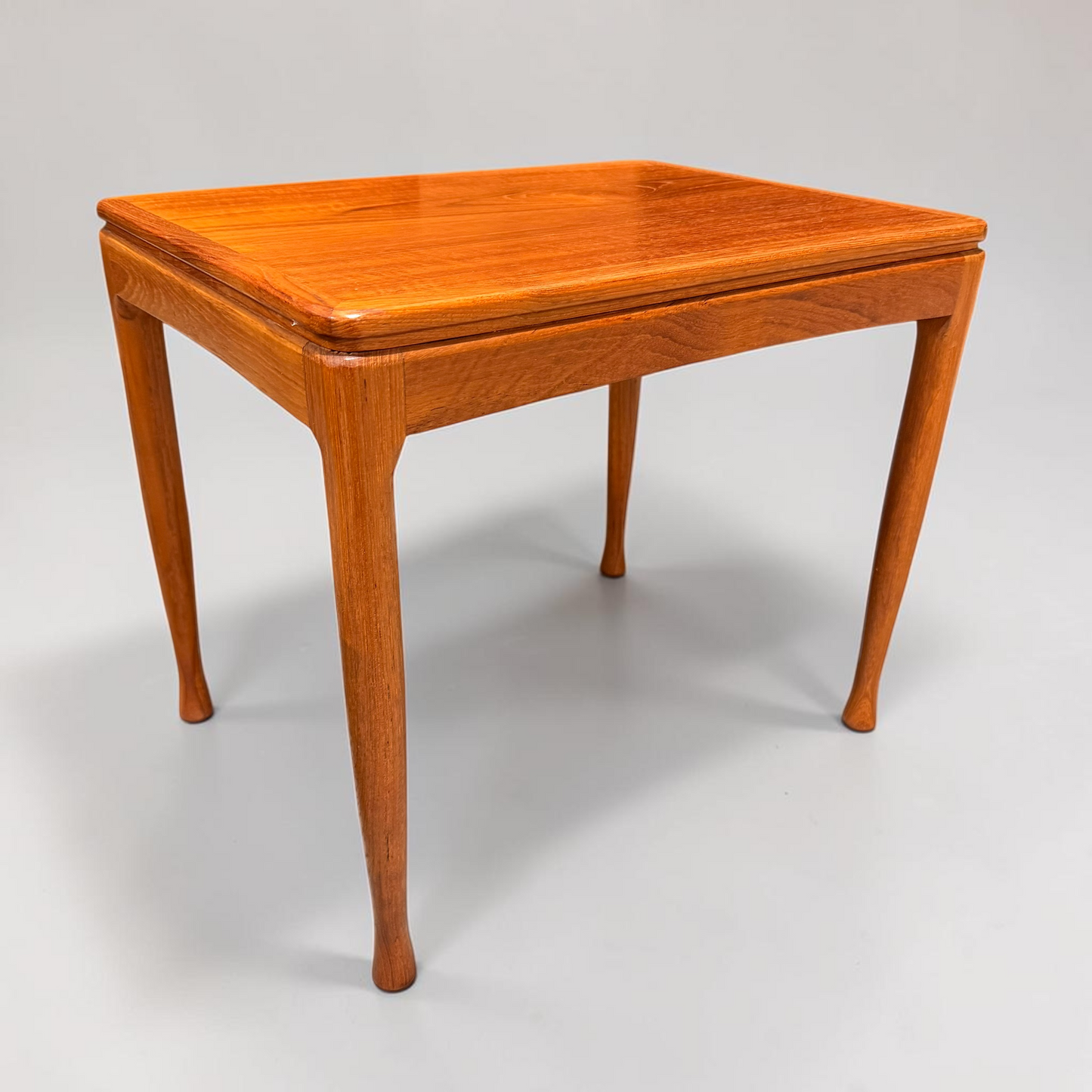 A rare set of Alpa Teak Nesting Tables (set of 3), showcasing Australian mid-century modern style, are pictured with polished surfaces and sleek lines against a plain light gray background.