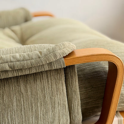 Close-up of a Pair of Tessa Monaco Arm Chairs in sage green corduroy, featuring plush cushions and smooth, curved wooden armrests. The cozy, mid-century design creates comfort and style—like new (Revive).