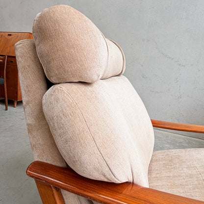 Close-up of a Vintage Mid Century Tessa T21 Swivel Chair (Revive) with beige upholstery and wooden armrests, featuring a cushioned backrest and headrest, set against a light gray wall in a minimalist room.