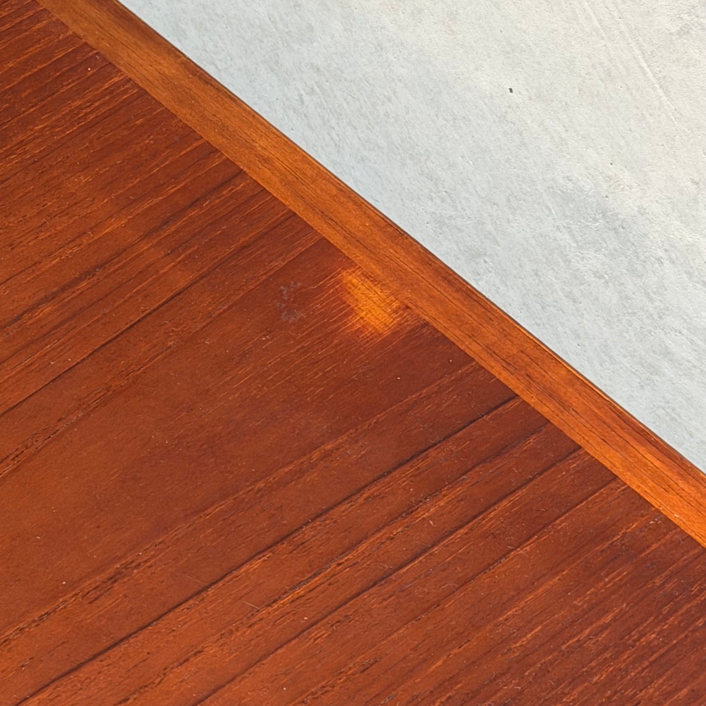 A close-up of the Vintage Mid-Century Parker 109 Nordic Extension Dining Table (Table Only) reveals a small, faded spot near the center and a border separating it from a light gray textured surface.