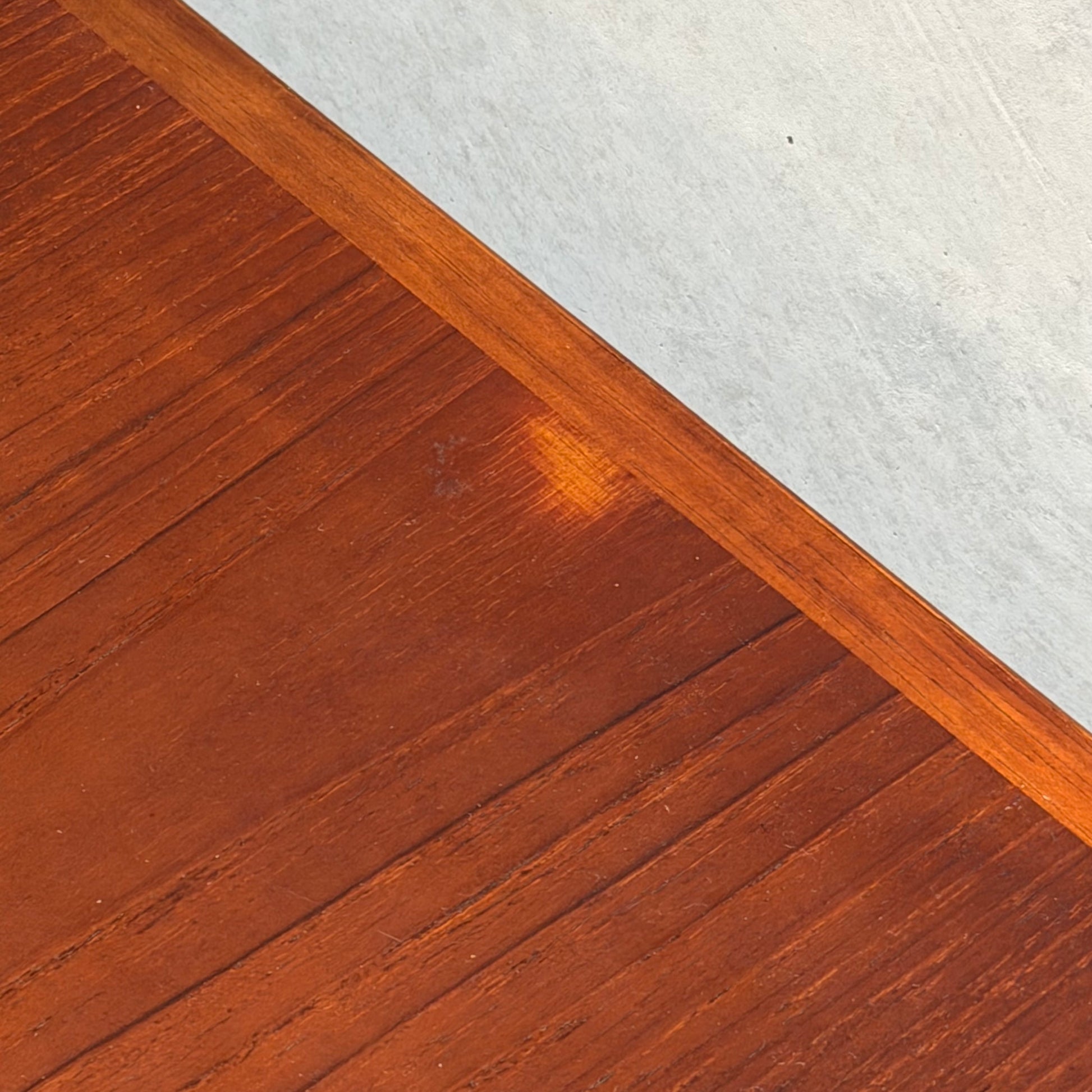 A close-up of the Vintage Mid-Century Parker 109 Nordic Extension Dining Table (Table Only) reveals a small, faded spot near the center and a border separating it from a light gray textured surface.