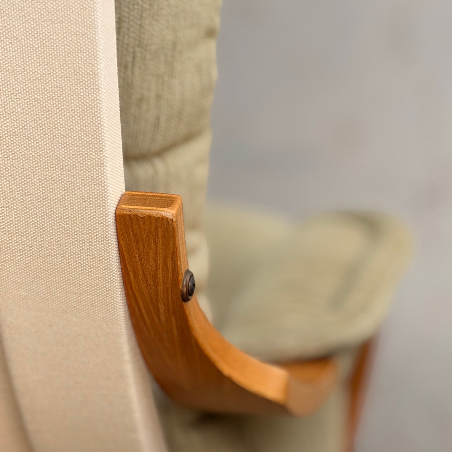 Close-up of the wooden armrest on a Pair of Tessa Monaco Arm Chairs—Sage Green Corduroy, Like New (Revive)—shows the textured upholstery and seat cushion, highlighting classic mid-century design in soft, neutral tones.