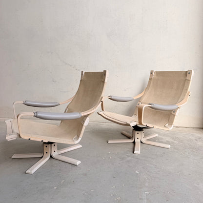 A pair of Tessa Ferrara Swivel Armchairs (Revive) with high mesh backs and swivel bases evoke mid-century Australian style, reminiscent of vintage Tessa Furniture, set on a concrete floor against a plain light wall.
