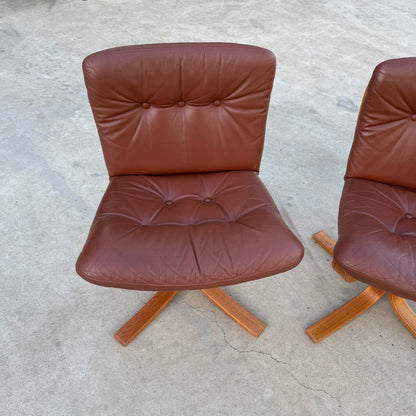 A Rare Set of 4 Vintage Joe Rufenacht Lounge Chairs in Howe Leather, featuring button-tufted upholstery and wooden crossed legs, showcases Scandinavian-inspired design on a concrete surface. Another chair from the set is partially visible on the right.