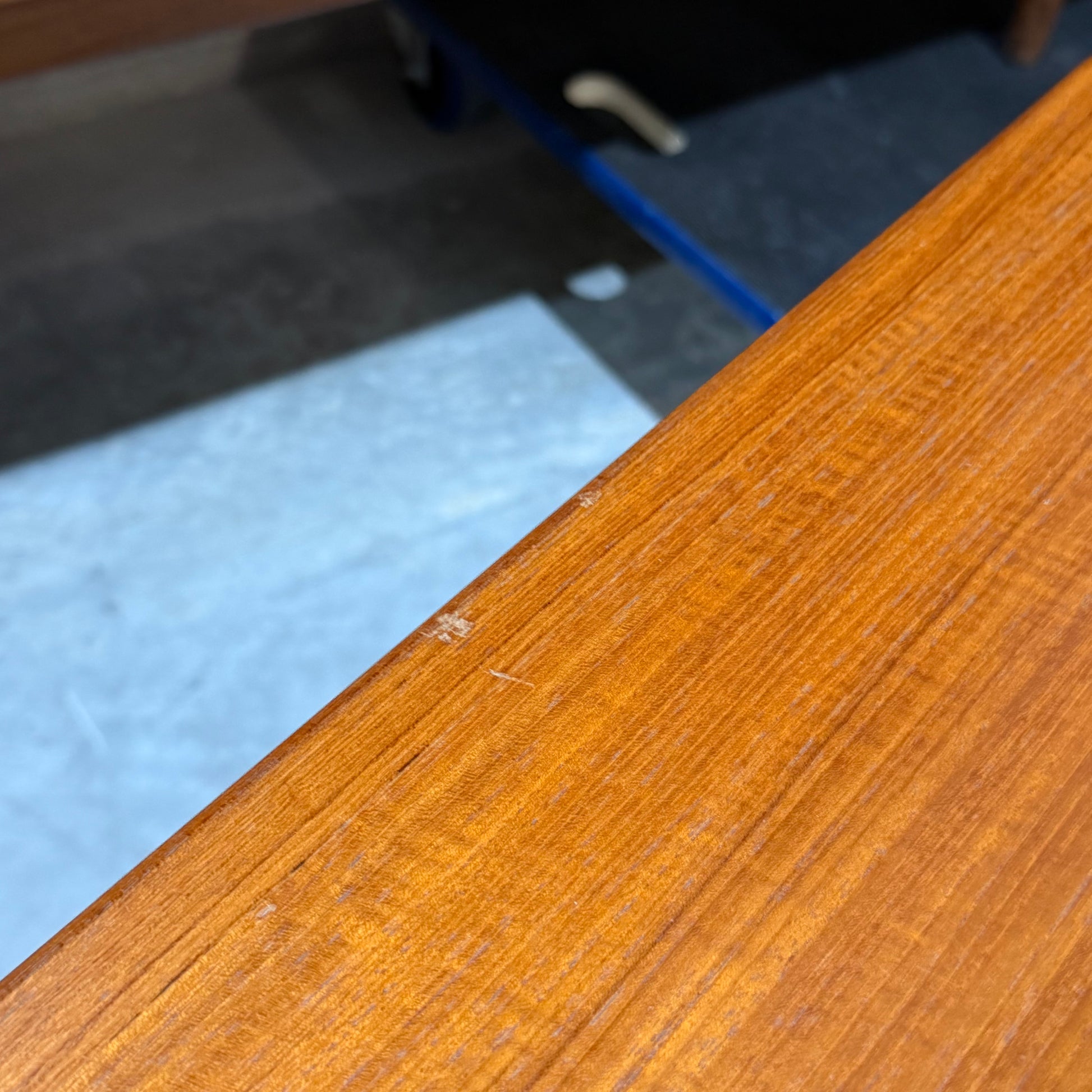 Close-up of a Rare set of Alpa Teak Nesting Tables – Set of 3, Australian Mid-Century Modern (Revive), showing edge wear. Tiled floor and a blue cart appear in the background, highlighting this timeless furniture style.