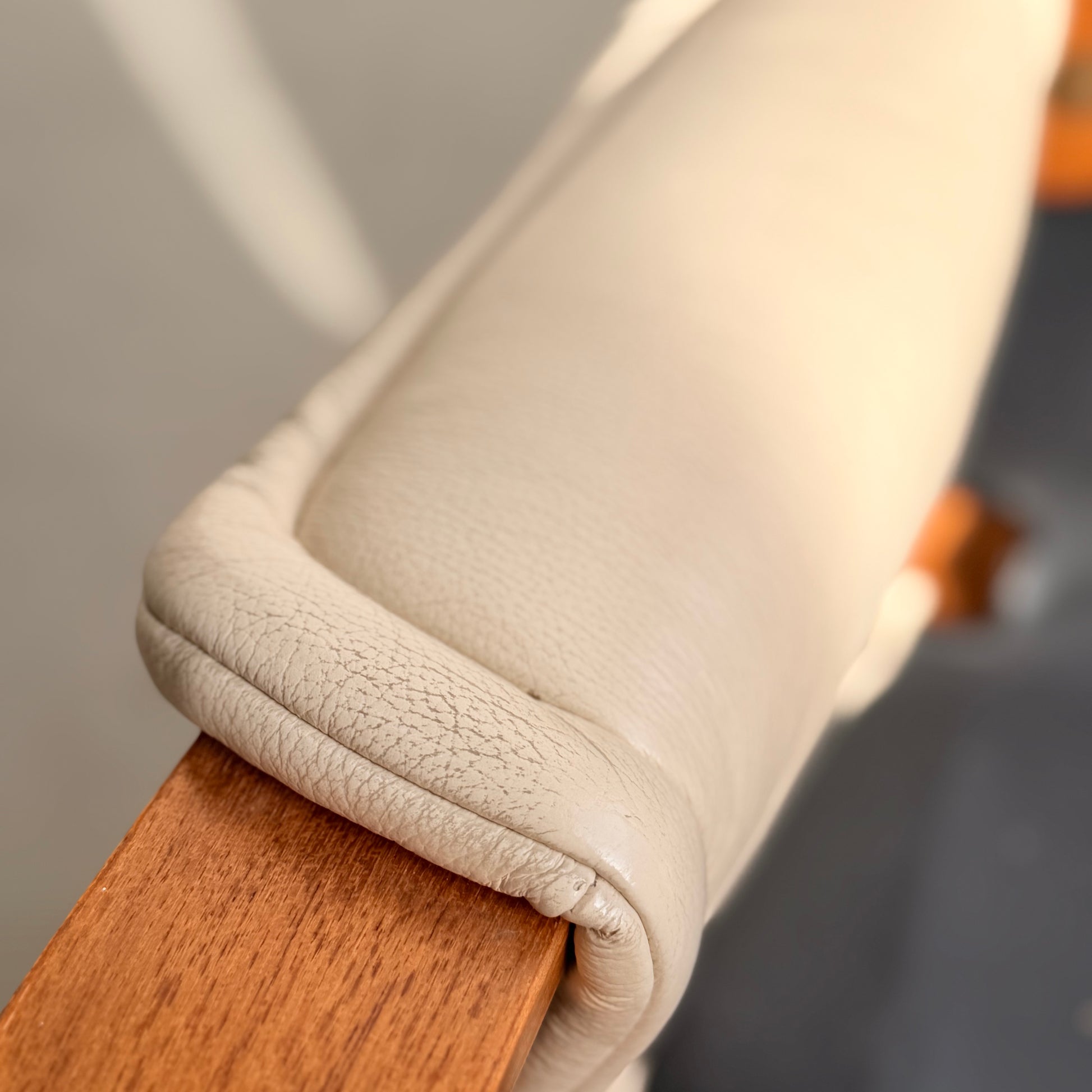 Close-up of the Tessa Austin Blonde Leather Armchair (Revive) armrest cover wrapped around wood, with soft natural lighting highlighting the blonde leather's texture. The background is softly blurred.