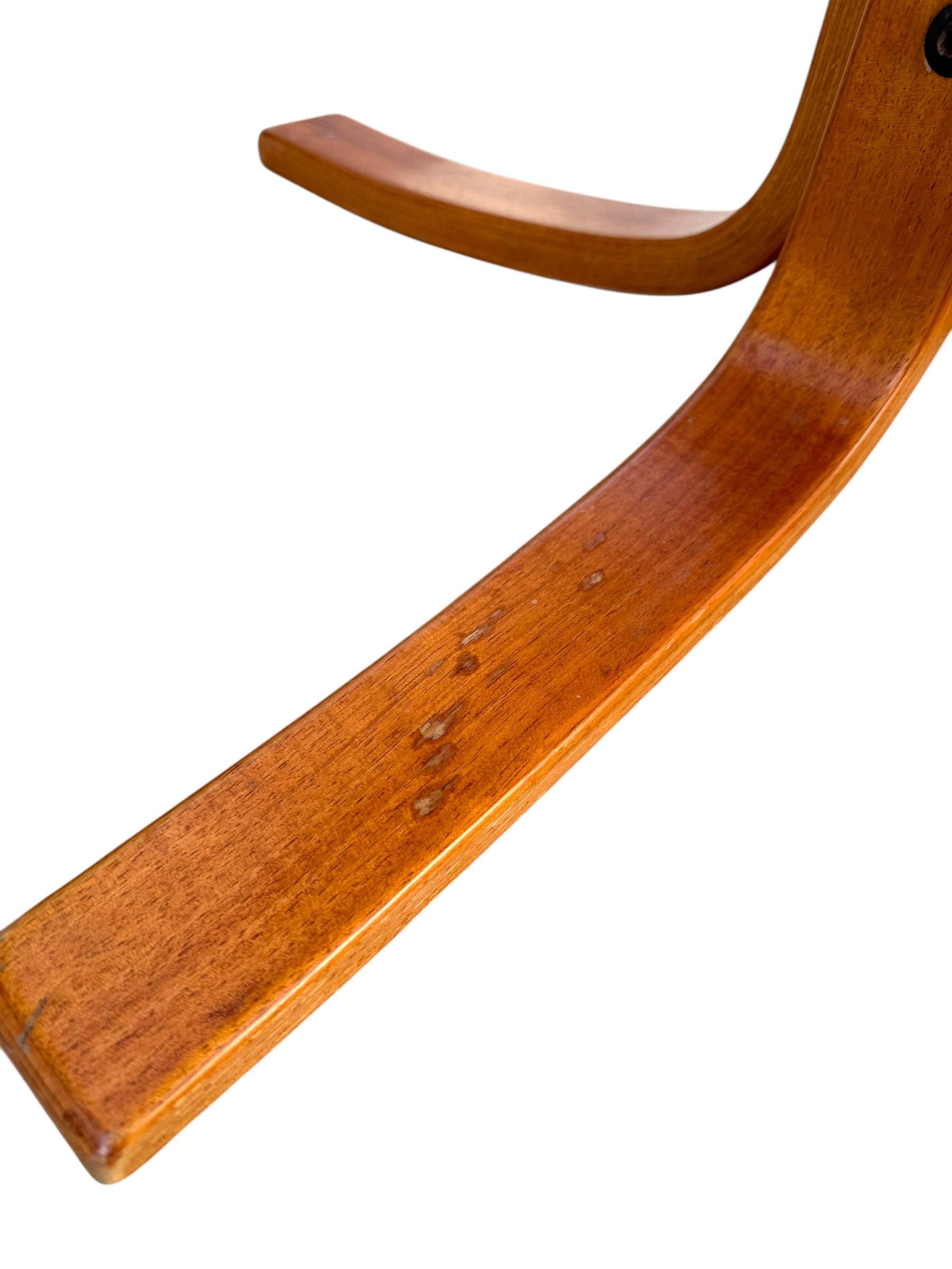 Close-up of a curved wooden leg from a Rare Set of 4 Vintage Joe Rufenacht Lounge Chairs – Howe Leather, showing scratches and spots on the polished surface; design echoes classic Scandinavian style, isolated on white.