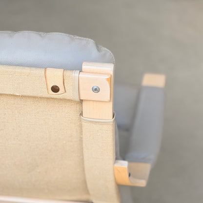 Close-up of the top corner of a Pair of Tessa Ferrara Swivel Armchairs (Revive), featuring light wood frames, beige canvas backrests, and grey cushioned headrests—a stunning example of mid-century Australian design. Blurred background.