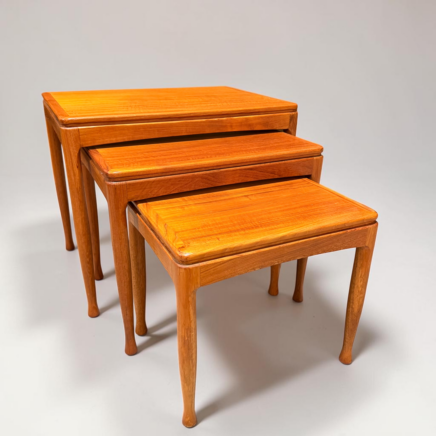 A Rare set of Alpa Teak Nesting Tables – Set of 3 features polished finishes and elegant legs, arranged on a plain white background, celebrating timeless Australian Mid-Century Modern design.