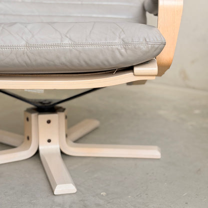 A close-up of the Pair of Tessa Ferrara Swivel Armchairs (Revive) highlights their padded light gray leather seats and backrests, exemplifying refined mid-century Australian design on a smooth, light-colored floor.