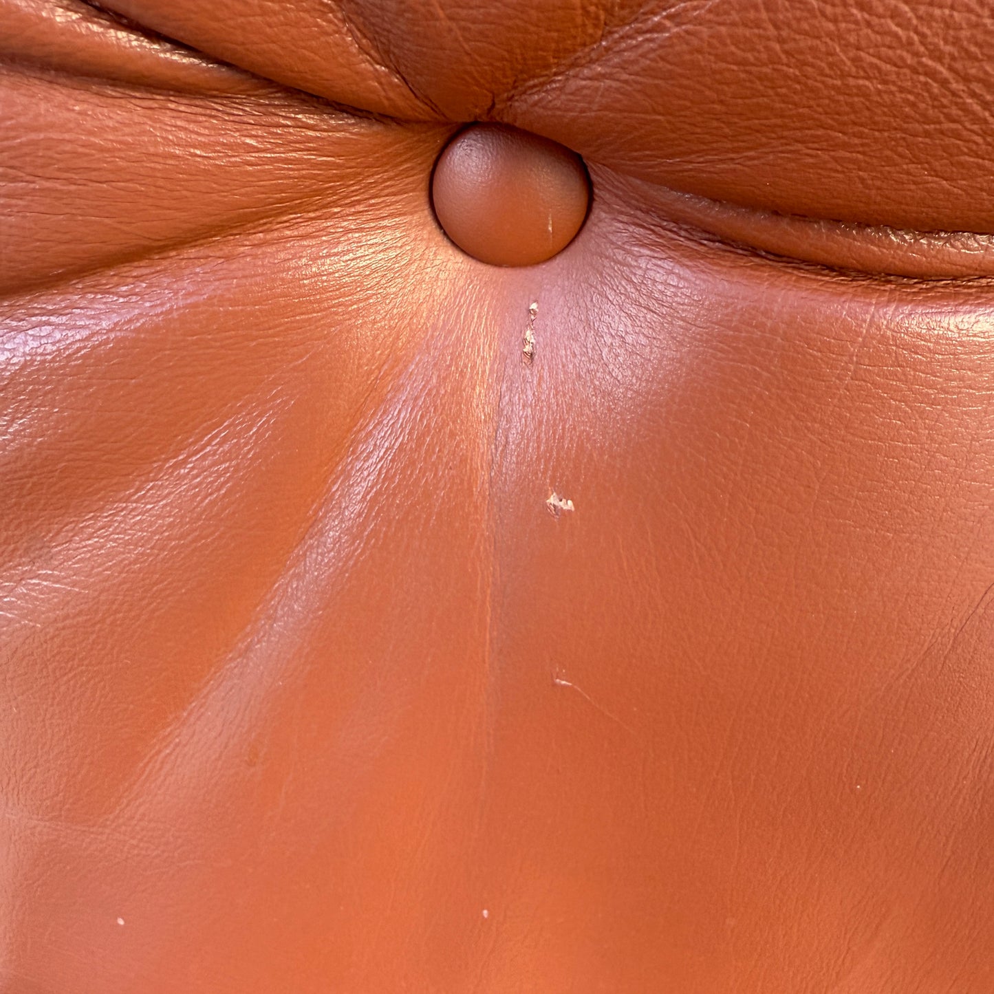 Close-up of a brown Howe leather surface with center button tuft and minor scratches—authentic details found on the Rare Set of 4 Vintage Joe Rufenacht Lounge Chairs.