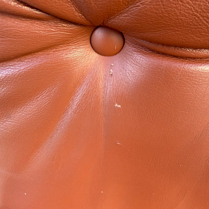 Close-up of a brown Howe leather surface with center button tuft and minor scratches—authentic details found on the Rare Set of 4 Vintage Joe Rufenacht Lounge Chairs.