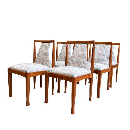 A set of six Vintage CRO Teak Dining Chairs (Revive) with light floral upholstery is arranged in two staggered rows on a white background, showcasing their mid-century modern design.