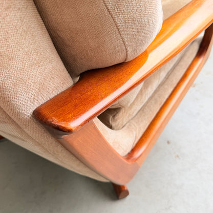 Close-up of the Vintage Mid Century Tessa T21 Swivel Chair (Revive), featuring beige upholstery, a smooth polished wooden frame and armrest that highlight the fabric's texture and warm wood tone, resting on a light-colored floor.